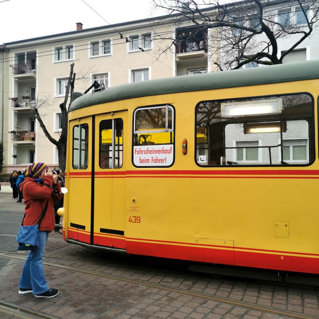 Frau fotografiert historische Straßenbahn in Karlsruhe