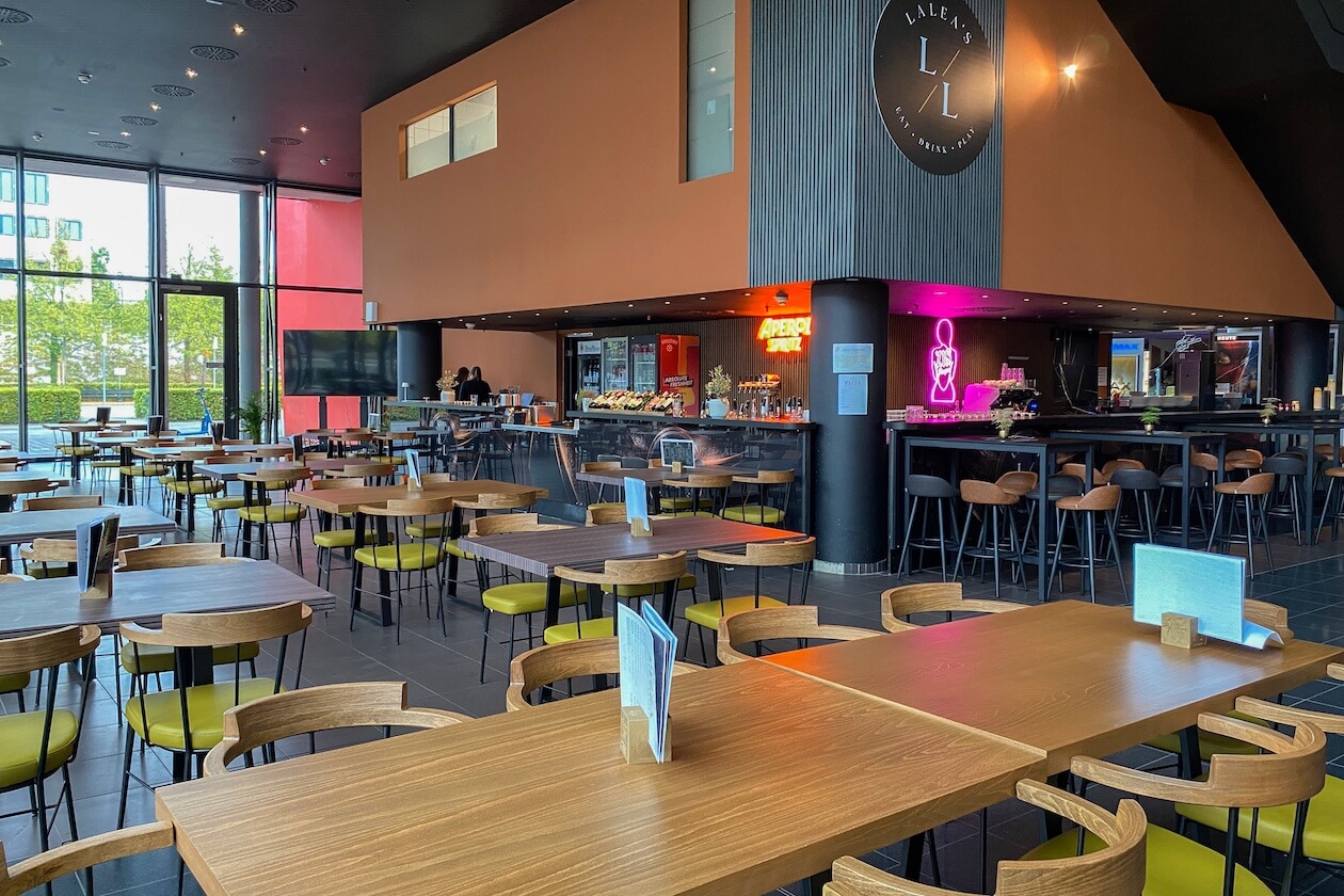 Gastraum des Laleas Eat & Drink im Filmpalast am ZKM Karlsruhe mit Holztischen und Bar 