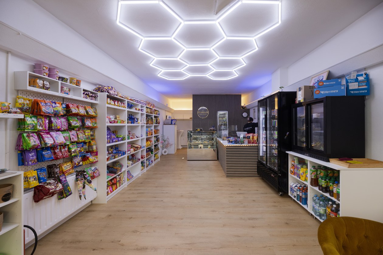 Blick in das Mariam Café & Kiosk in Karlsruhe mit Snackregalen, Kühlschränken und Lichtdecke in Wabenform